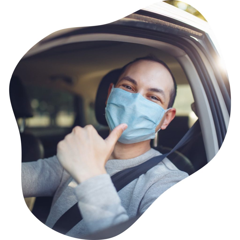 A driver wearing a face mask giving a thumbs-up.